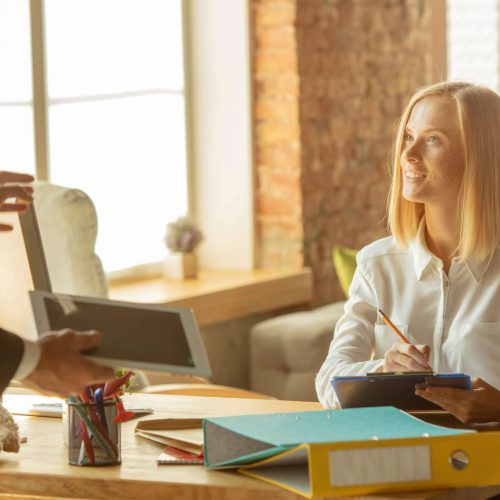 A young businesswoman moving in the office, getting new work place. Young caucasian female office worker meets her colleague or workmate after promotion. Business, lifestyle, new life concept.